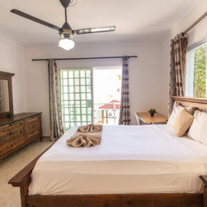 Habitación cama matrimonial con balcón y baño privado.
