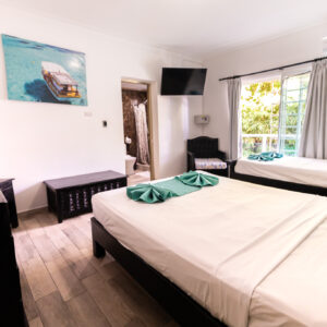 Habitación cama matrimonial y una cama sencilla con balcón y baño
